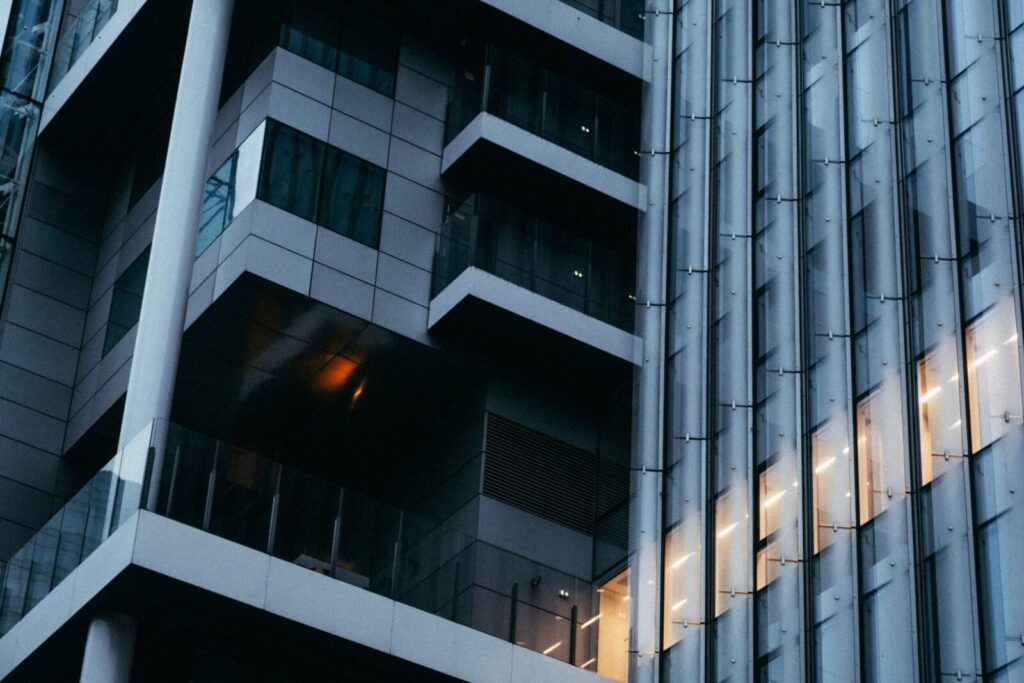 Low angle view of modern office building with glass facade and ambient lighting at dusk.