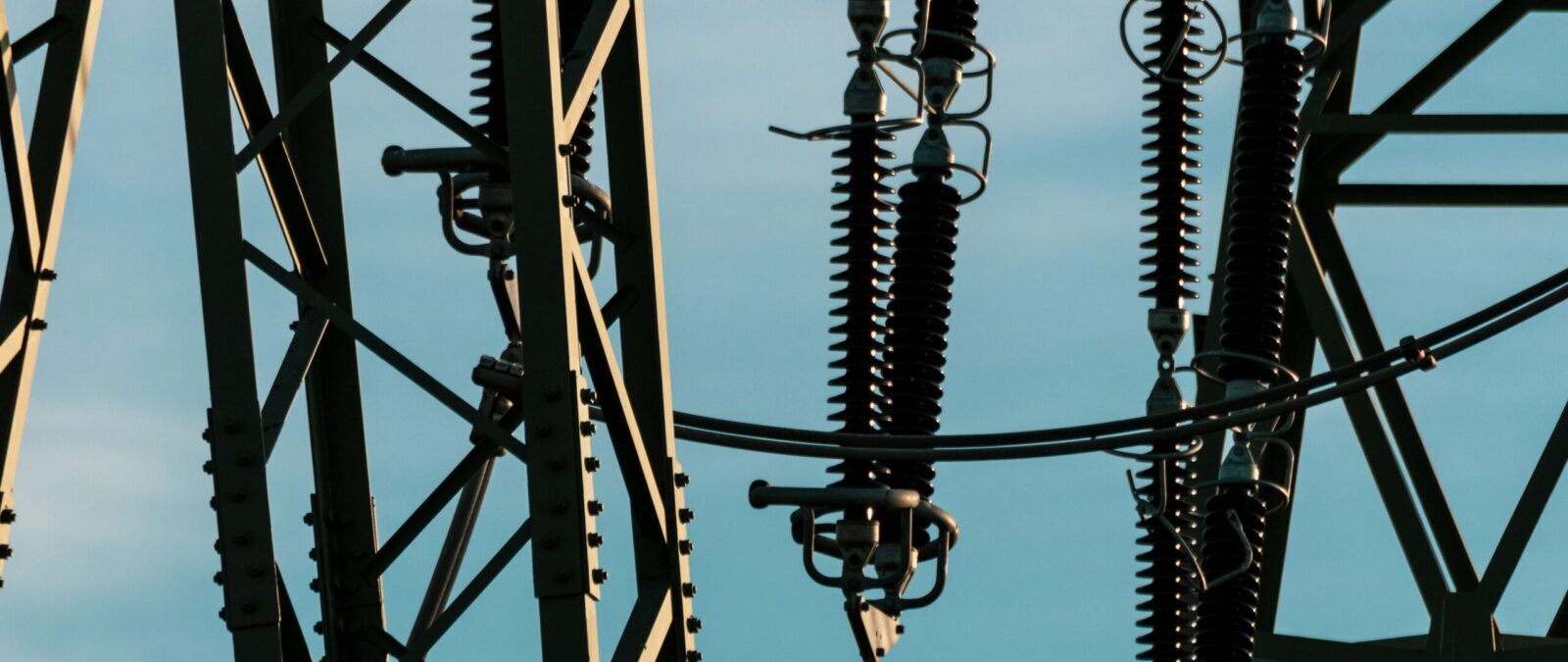 Detailed shot of power lines and electrical insulators set against a vivid blue sky.