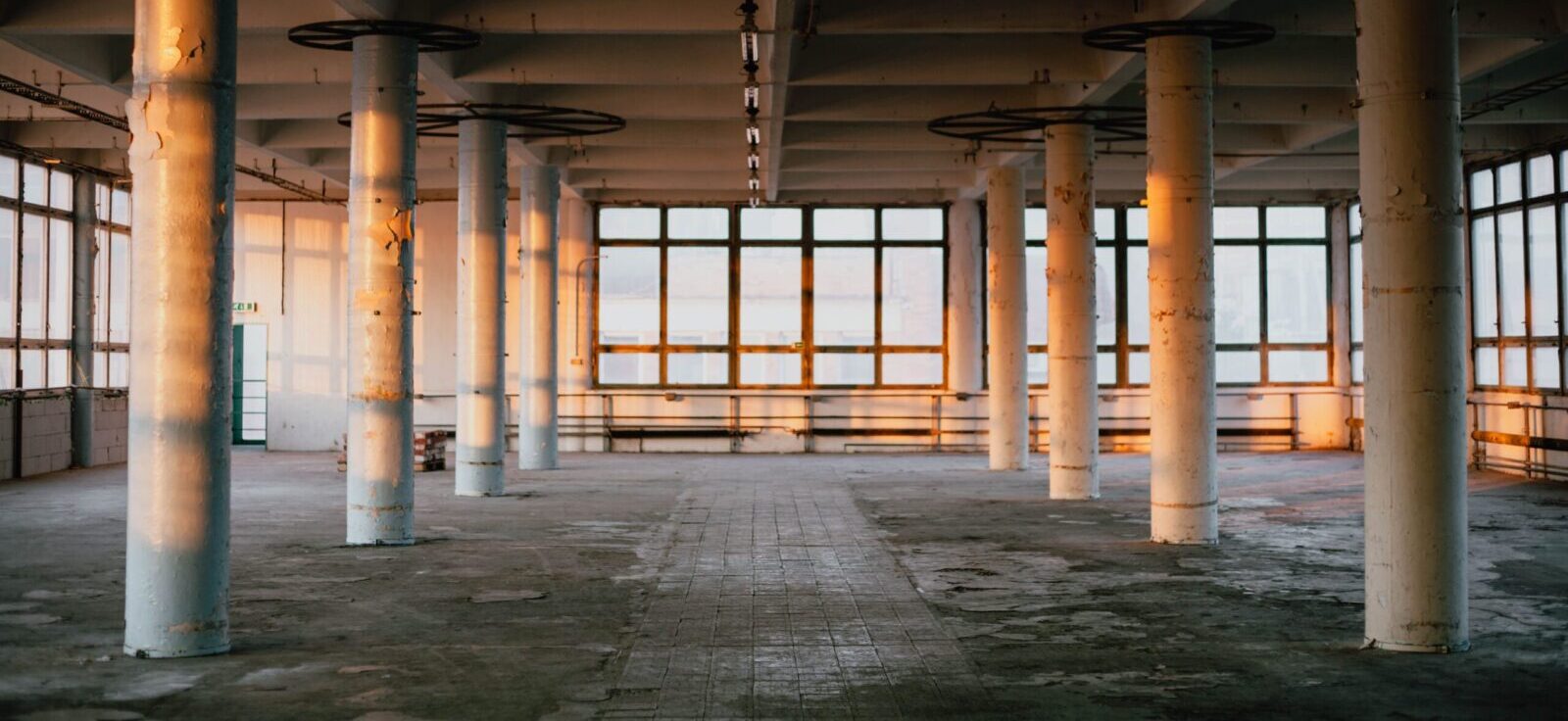 Sunlit empty factory interior with tall columns creating an industrial feel.