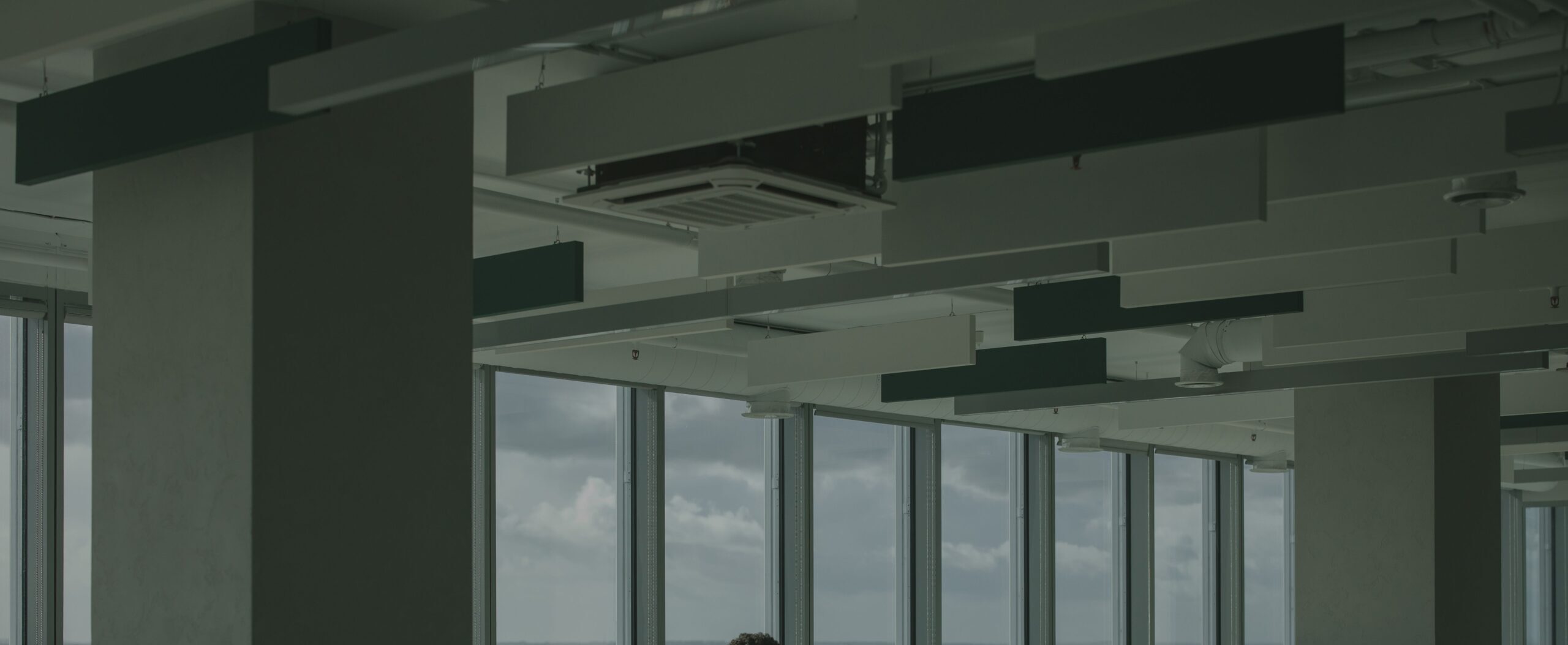 a man works alone in a spacious, modern office with large windows and natural light.